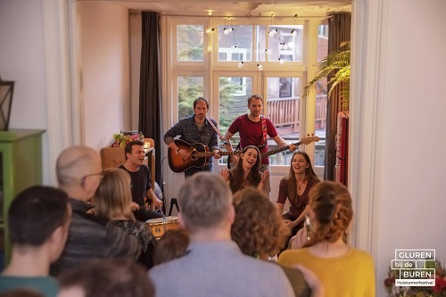 Maarten J Eykman, fotograaf, gitaar en zang in huiskamer met publiek
